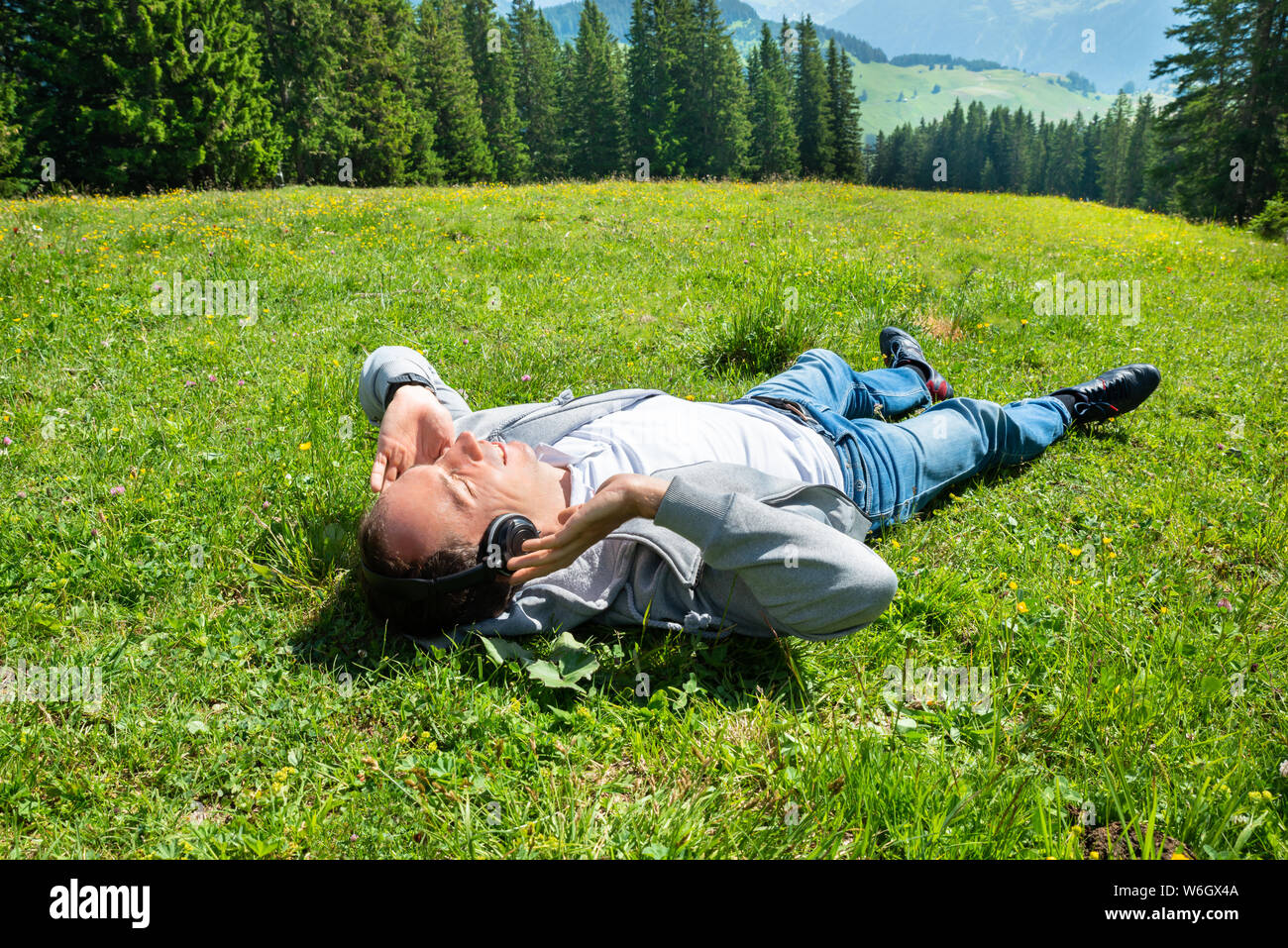 Man Entspannende liegen im Bereich der Grass Musik hören In den Bergen Stockfoto