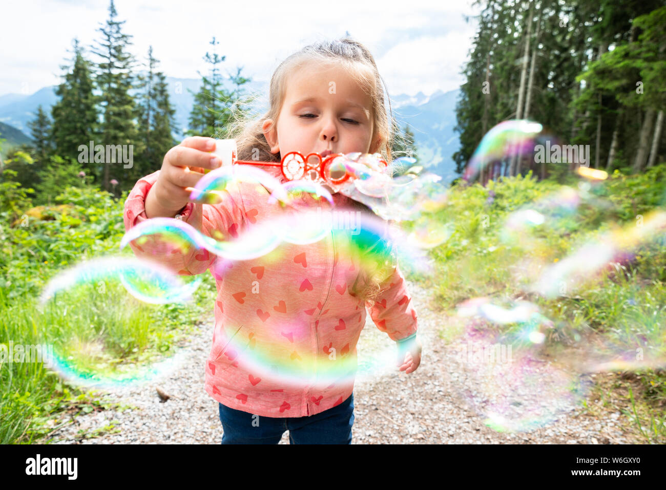 Mädchen bläst Seifenblasen an einem sonnigen Tag im Park Stockfoto
