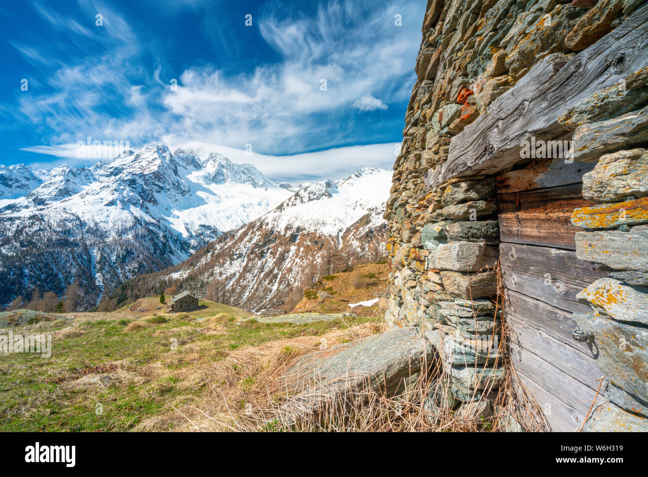 Alpine Hütte aus Stein und Monte Disgrazia bedeckt mit Schnee im Frühling Blick von der Alpe Oro, Valmalenco, Valtellina, Lombardei, Italien Stockfoto