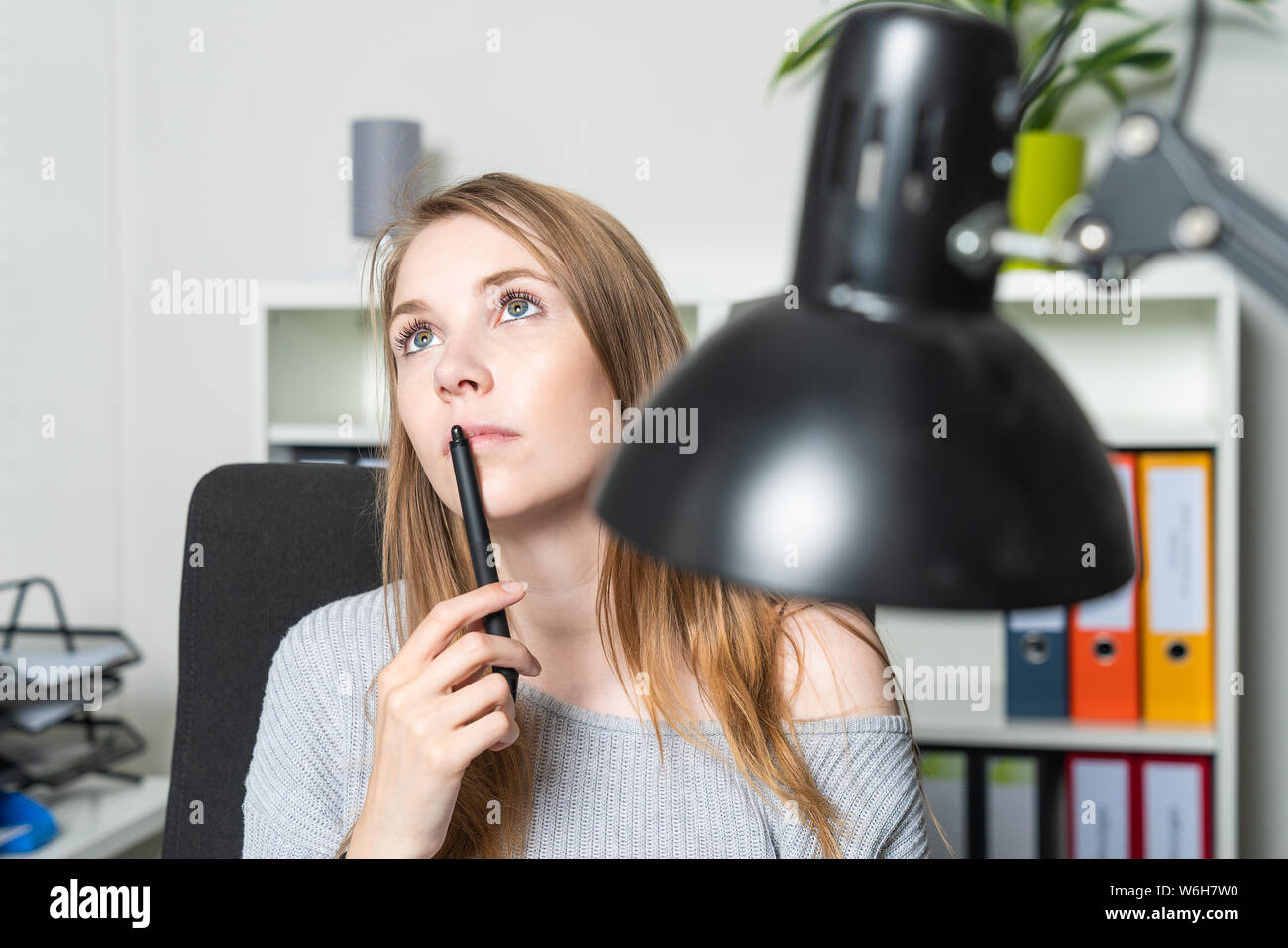 Eine junge Frau im Büro ist in Gedanken verloren Stockfoto
