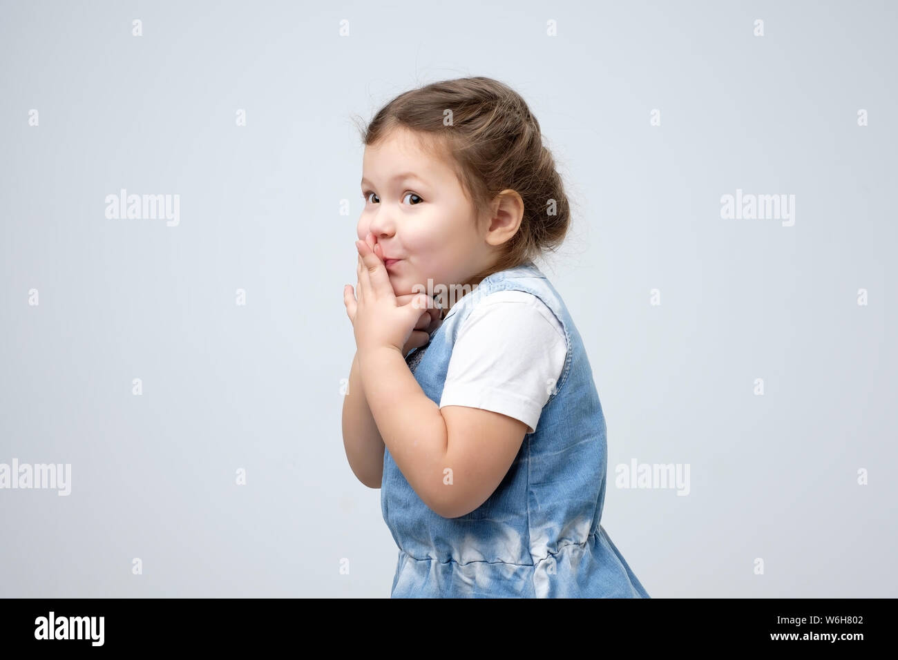 Kleines Mädchen Mund mit den Händen warten auf Geschenk überrascht abgedeckt Stockfoto