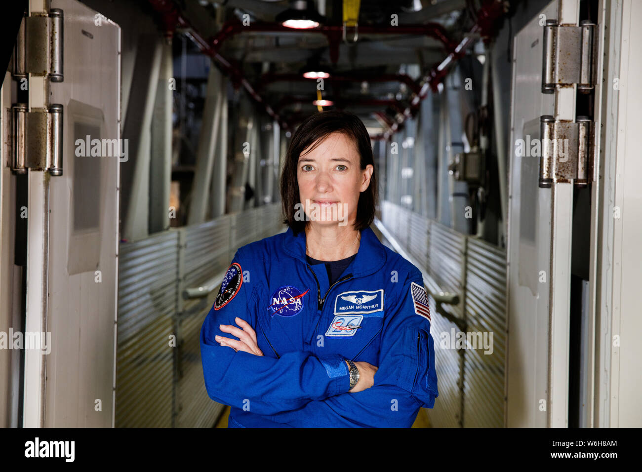 NASA-Astronautin Megan McArthur Posen für ein Portrait das Tragen der blauen Fliegeroverall - vor der Besatzung Zugang Arm der Mobile Launcher im Vehicle Assembly Building im Kennedy Space Center Juni 25, 2019 in Cape Canaveral, Florida. Stockfoto
