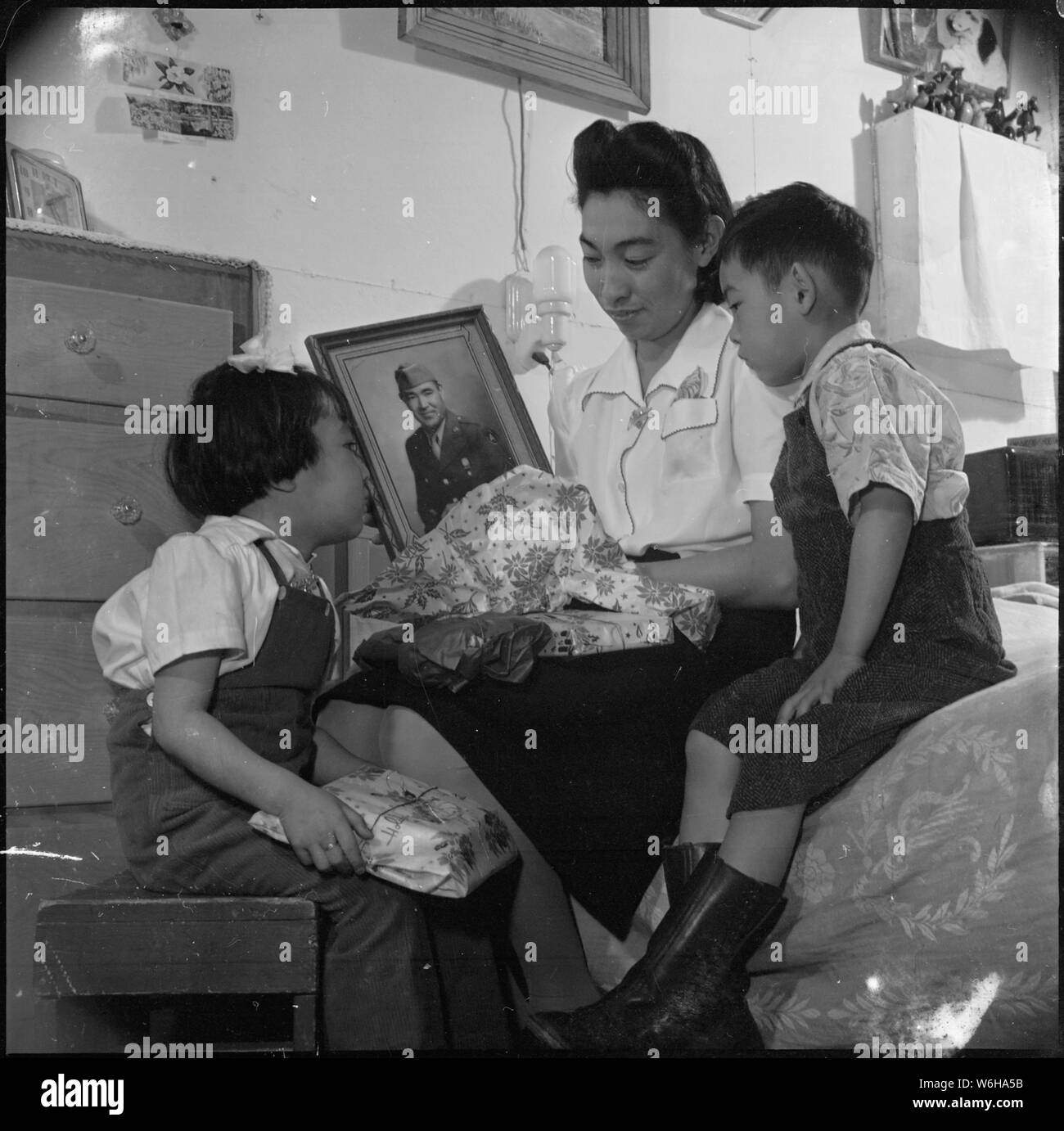 Granada Relocation Center, Amache, Colorado. Wenig Peggy und Bobby Miyake nicht zu Weihnachten t. . .; Umfang und Inhalt: Der vollständige Titel für dieses Foto lautet: Granada Relocation Center, Amache, Colorado. Wenig Peggy und Bobby Miyake nicht einen Weihnachtsbaum in ihrer Kaserne zimmer Home haben an der Granada Relocation Center. Es gab einfach keine Bäume. Aber Weihnachten ist noch Santa Claus zu Ihnen, als Mutter packt Anfang Geschenke, unter ihnen, ein Bild von ihrem Vater, Bill Miyaki, der ein Soldat in der Armee der Vereinigten Staaten. Die Familie wurde von der Westküste evakuiert zusammen mit Stockfoto