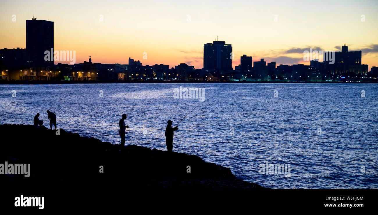 Silhouetten der Fischer entlang des Malecon mit einer Silhouette Skyline in der Dämmerung, Havanna, Kuba Stockfoto