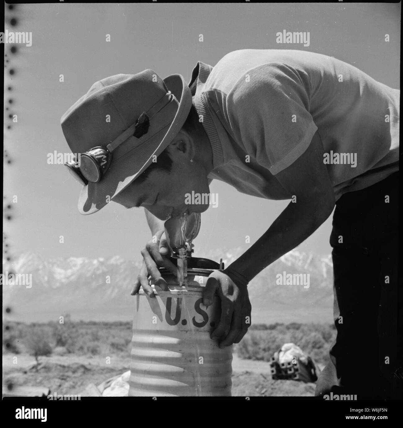 Manzanar Relocation Center, Manzanar, Kalifornien. Masaro Takahashi, 19, umsiedler Landwirt aus Malibu. . .; Umfang und Inhalt: Der vollständige Titel für dieses Foto lautet: manzanar Relocation Center, Manzanar, Kalifornien. Masaro Takahashi, 19, umsiedler Landwirt aus Malibu Beach, nimmt einen Schluck von einem tragbaren Armee Kantine auf der Farm am Relocation Center. Stockfoto