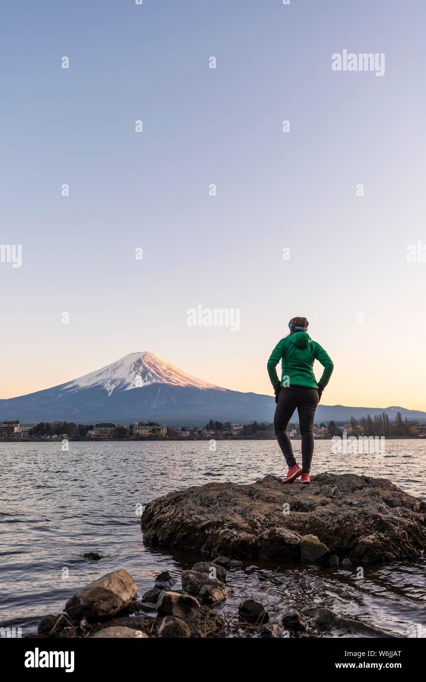 Abendstimmung, junge Frau auf einem Stein im Wasser und der Blick in die Ferne, Blick über Lake Kawaguchi, zurück Vulkan Mt. Fuji, Yamanashi Stockfoto