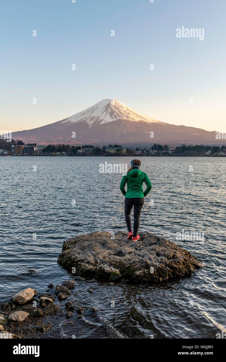 Abendstimmung, junge Frau auf einem Stein im Wasser und der Blick in die Ferne, Blick über Lake Kawaguchi, zurück Vulkan Mt. Fuji, Yamanashi Stockfoto