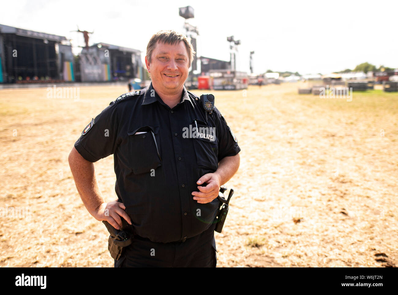 Wacken, Deutschland. Juli 31, 2019. Thomas Körn, Polizeichef der Brunsbüttel Polizeistation, steht im Infield des Wacken Open Air Festival, wo die letzten Bauarbeiten abgeschlossen sein wird. Körn ist der stellvertretende Vorsitzende der Polizei Führung für die größten Heavy Metal Festival der Welt, so die Veranstalter. (Dpa: Damals und heute: Das wacken Polizist, der mit uns Seit 1998) Credit: Axel Heimken/dpa/Alamy leben Nachrichten Stockfoto