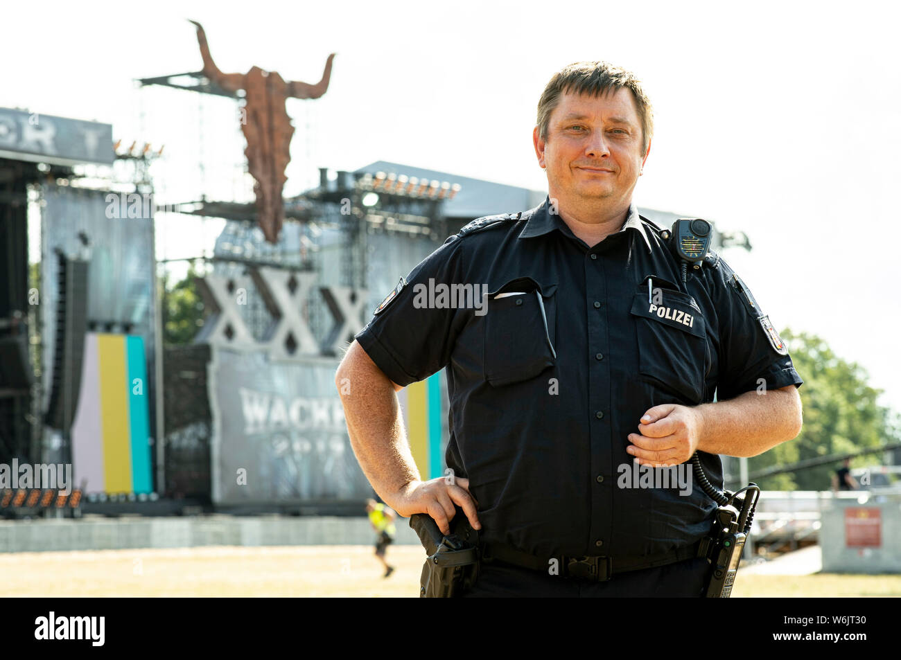 Wacken, Deutschland. Juli 31, 2019. Thomas Körn, Polizeichef der Brunsbüttel Polizeistation, steht im Infield des Wacken Open Air Festival, wo die letzten Bauarbeiten abgeschlossen sein wird. Körn ist der stellvertretende Vorsitzende der Polizei Führung für die größten Heavy Metal Festival der Welt, so die Veranstalter. (Dpa: Damals und heute: Das wacken Polizist, der mit uns Seit 1998) Credit: Axel Heimken/dpa/Alamy leben Nachrichten Stockfoto