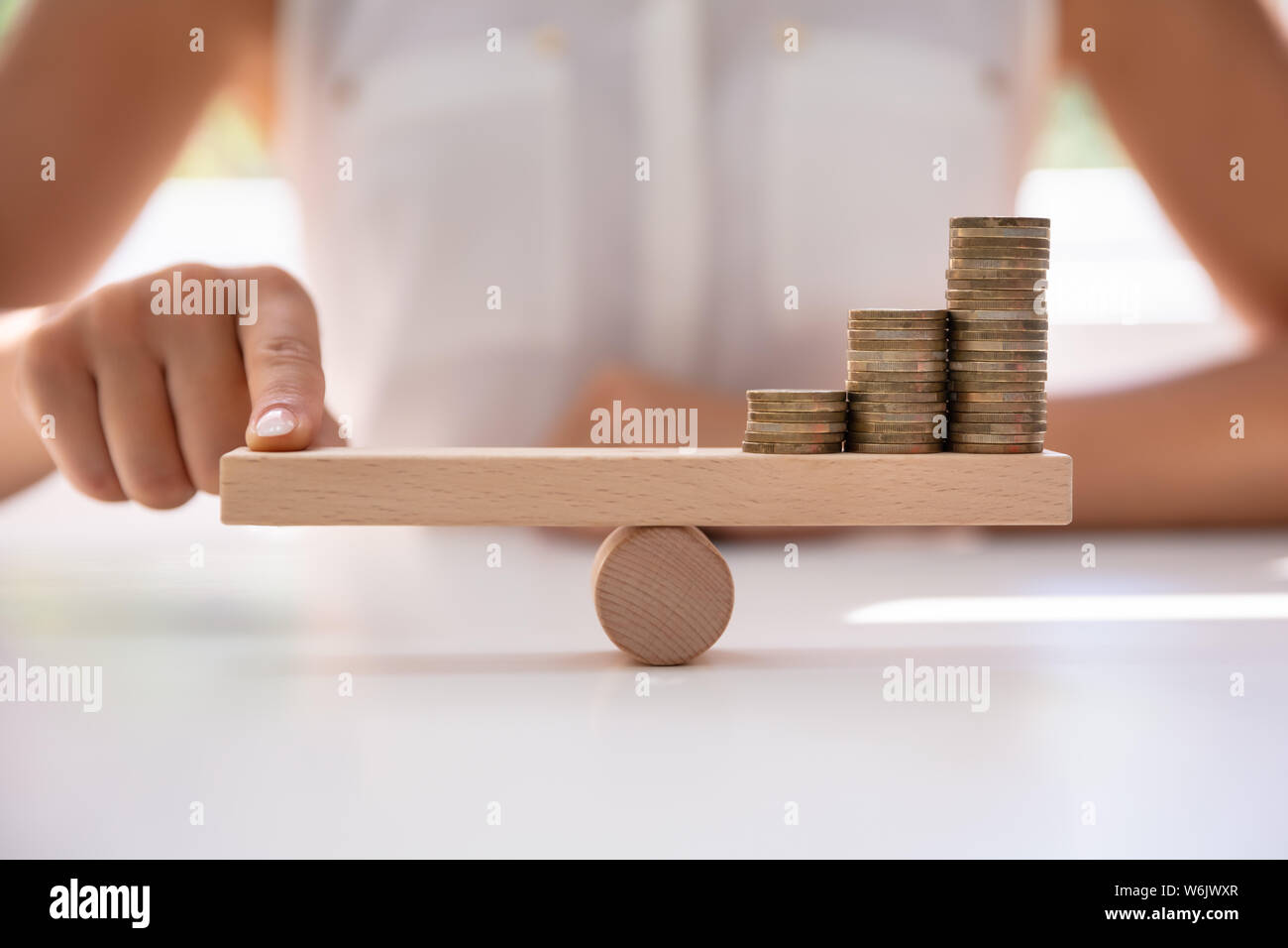 Nahaufnahme einer Businessperson Balancing erhöht Gestapelte Münzen mit Finger auf Wippe Stockfoto