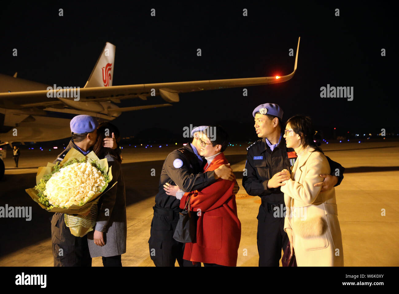 Drei Mitglieder der sechsten Team chinesischer Friedenstruppen Polizei zu Südsudan ihre Frauen umarmen, wie Sie an der Hangzhou Xiaoshan International Ai ankommen Stockfoto