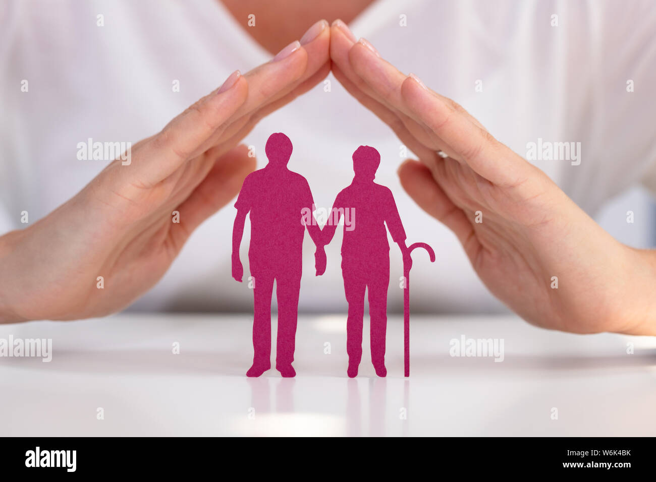 In der Nähe von Frau schützende Hand Senior Paar Ausschnitt Abbildungen über Weiß Schreibtisch Stockfoto