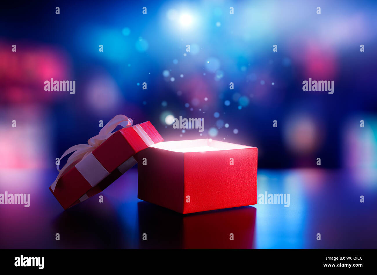 Red open Geschenkkarton mit magischen Licht gegen verwackelte Bokeh hellen Hintergrund Stockfoto