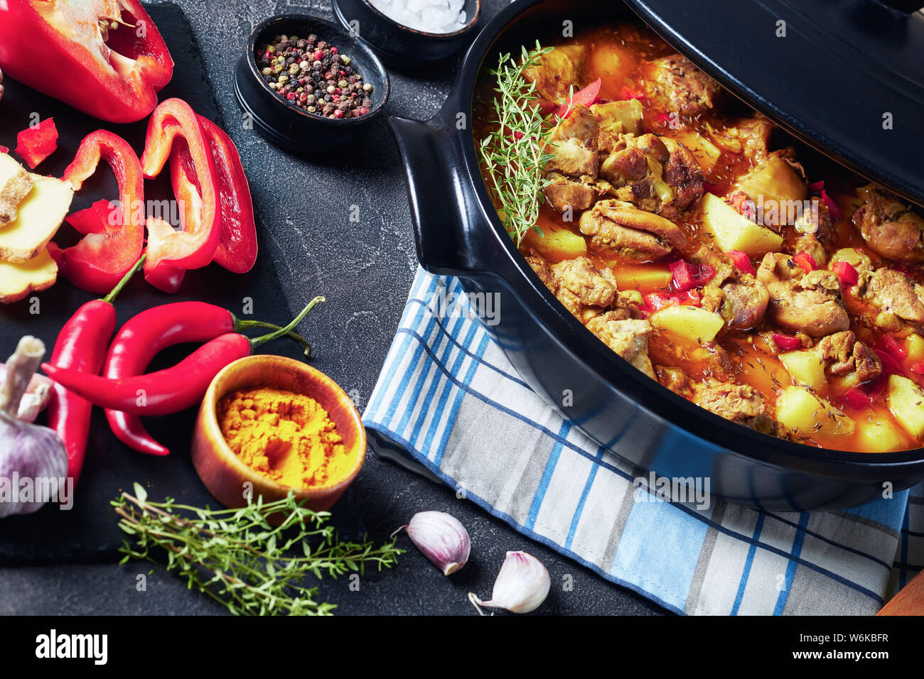 Spicy chicken entbeint Schenkel curry mit Kartoffel, Paprika, Gewürze in einem schwarzen Pan, karibische Küche, horizontale Ansicht von oben, close-up Stockfoto
