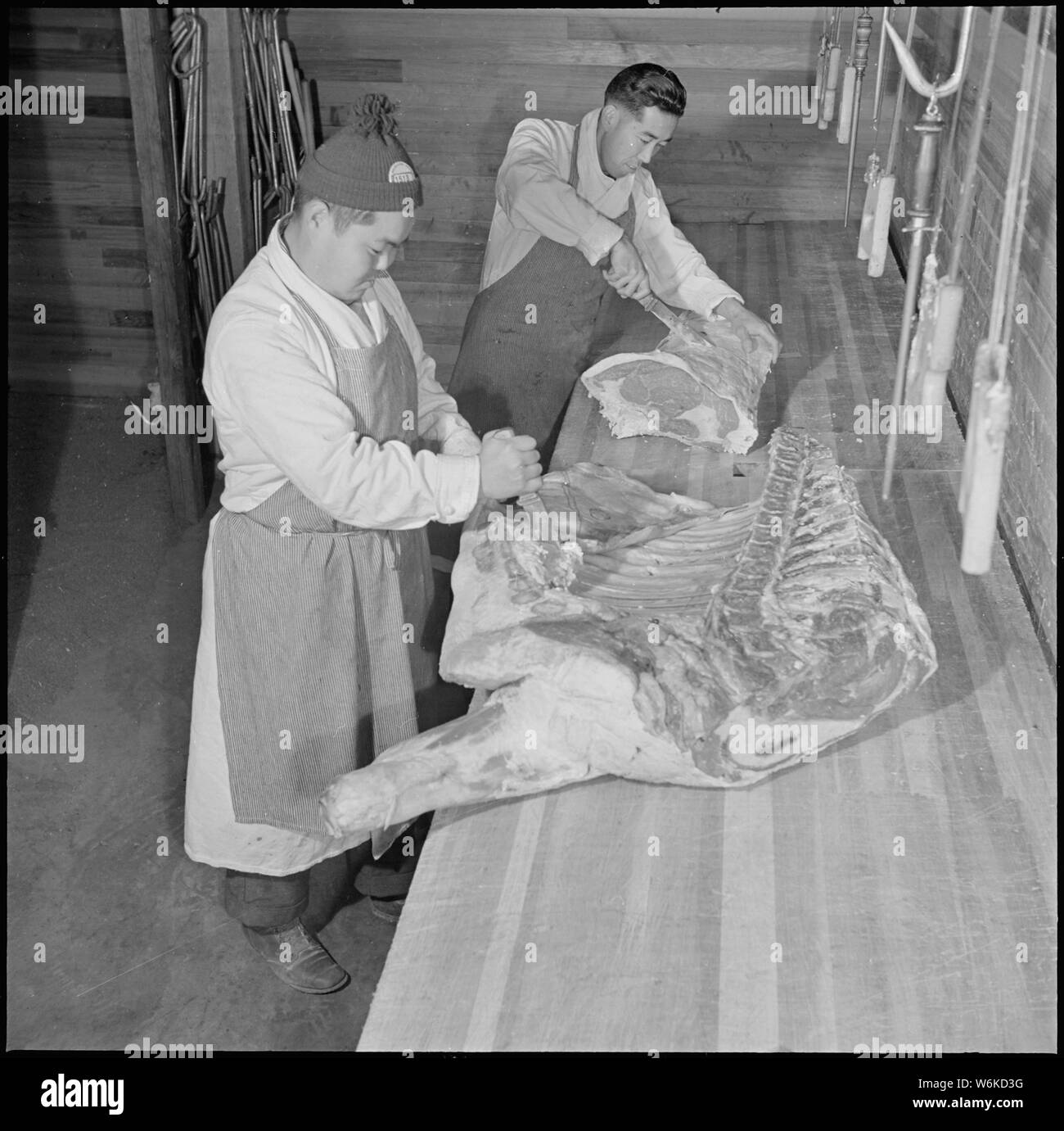 Rohwer Relocation Center, McGehee, Arkansas. Sam Takada und George Yohihara, ehemaliger Westküste aber. . .; Umfang und Inhalt: Der vollständige Titel für dieses Foto lautet: Rohwer Relocation Center, McGehee, Arkansas. Sam Takada und George Yohihara, ehemaliger Westküste Metzger, Schneiden von Fleisch für Center mess-Hallen. Mit fleisch Rationierung strikt nur erfahrene Metzger in der Verteilung der begrenzten Fleisch liefern zu verwirren - Halle Küchen tätig sind, eingehalten werden. Sie sind von der Mitte Bewohner, ehemalige Westküste Personen der japanischen Vorfahren recurited. Stockfoto