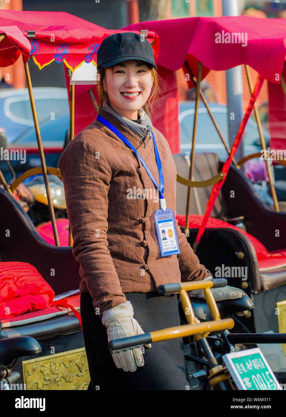 Chinesin Li Geyin, Mitglied der traditionell von Männern nur Dreirad fahren Team Houhai Baye, die Touren im Herzen von Peking leitet, steht in Fr Stockfoto