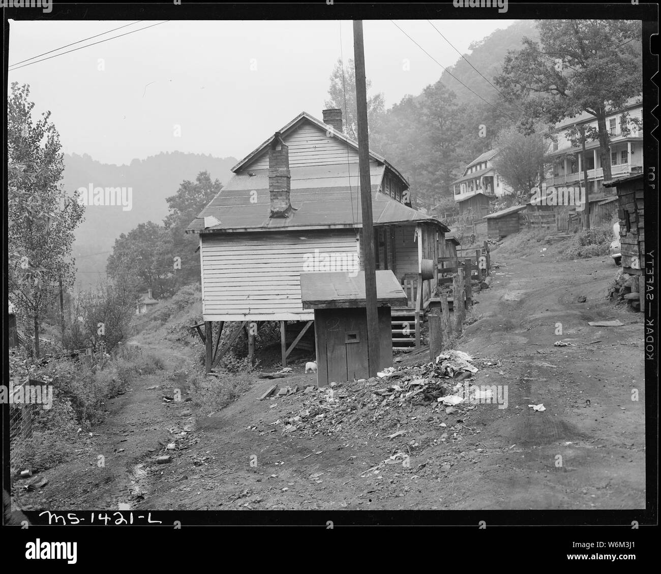 Seitenansicht des Zweifamilienhaus, in dem James Robert Howard Familie lebt. Unrat sammelt und zerfällt überall. Von Sickerwasser privies sammelt sich niedrige Stellen. Gilliam, Kohle und Koks, Gilliam Mine, Gilliam, McDowell County, West Virginia. Stockfoto