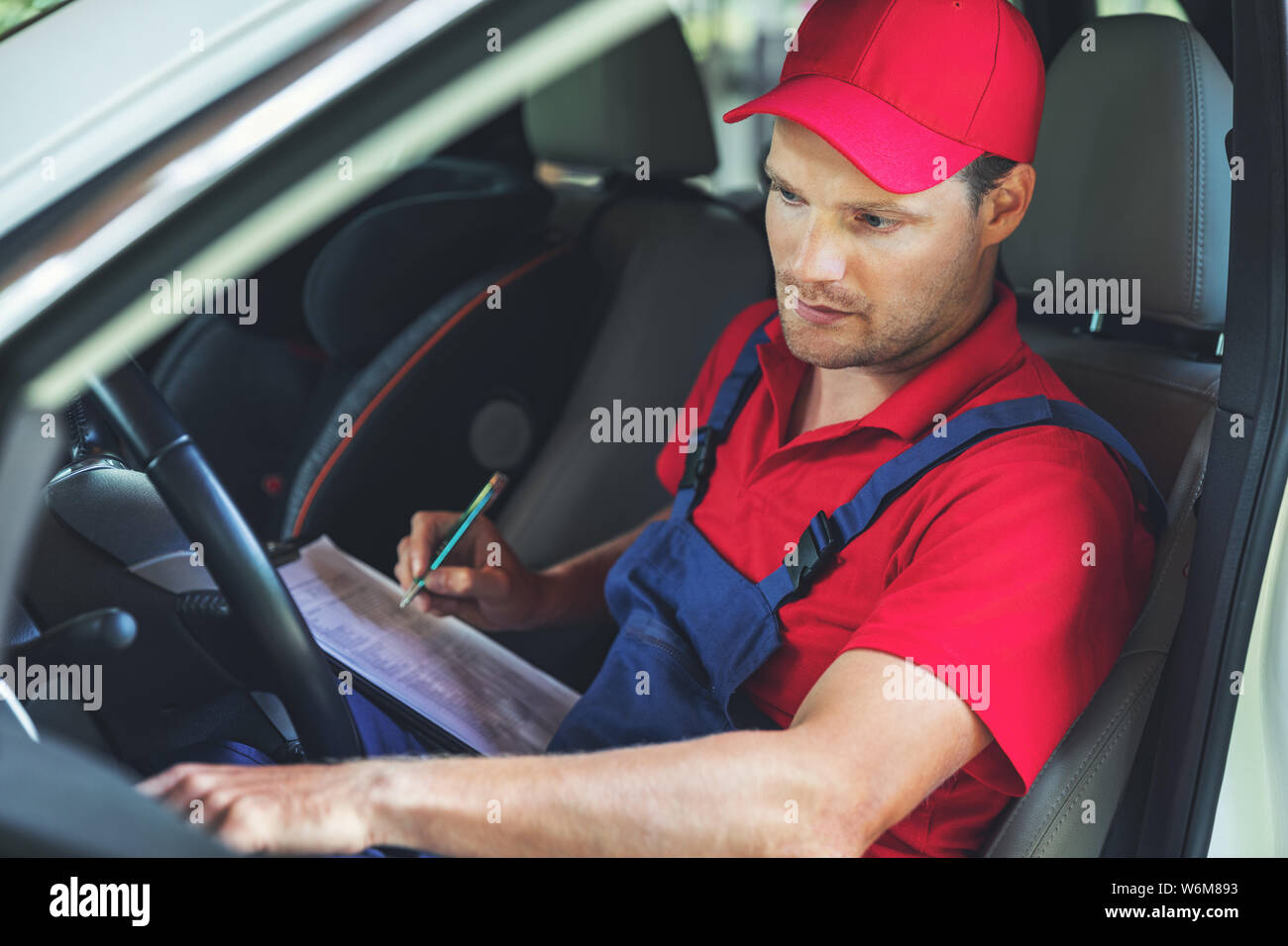 Technische Fahrzeuginspektion - Mann sitzt im Fahrzeug und überprüft das Armaturenbrett Stockfoto
