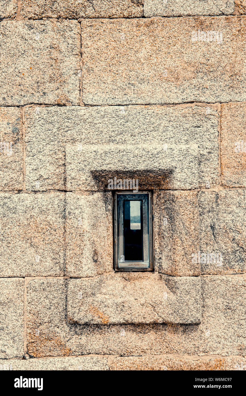 Vorderansicht des Granit stein Wand mit einem kleinen Fenster Stockfoto