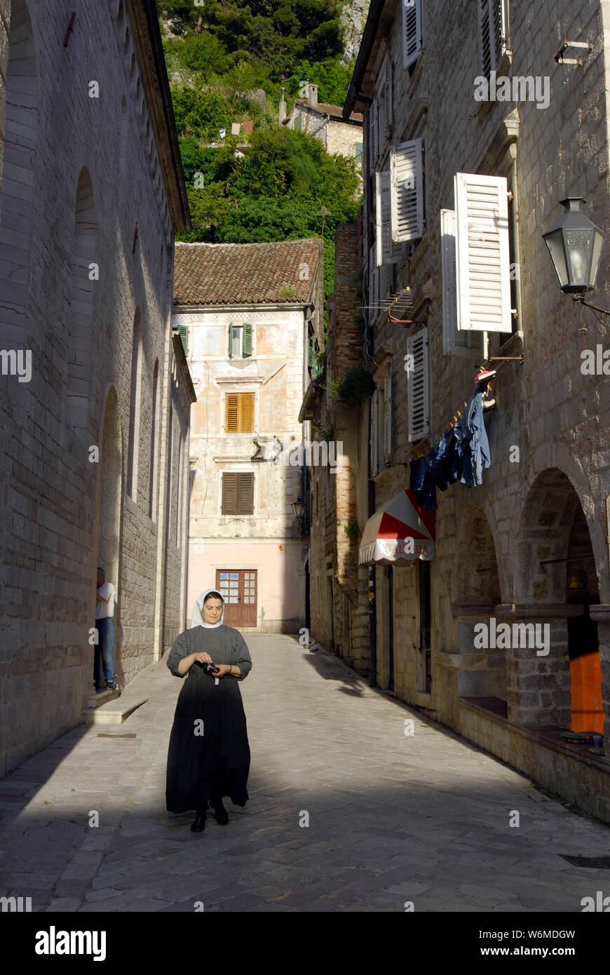 Nonne in Schwarz gekleidet geht hinunter die Straße der alten Stadt Stockfoto