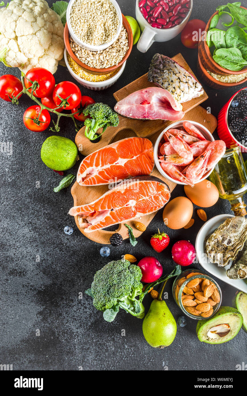 Pescetarian Diätplan Zutaten, gesunde und ausgewogene Lebensmittel essen, frisches Obst, Beeren, Fisch und Schalentiere Venusmuscheln, schwarzer Stein konkreten Hintergrund kopieren Stockfoto