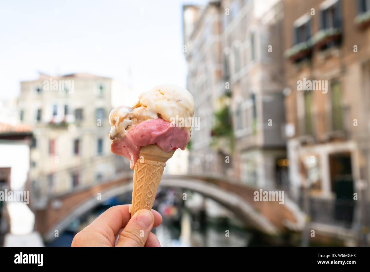 Person's Hand Eis Kegel Vor einem unscharfen alten Häusern in Venedig Stockfoto