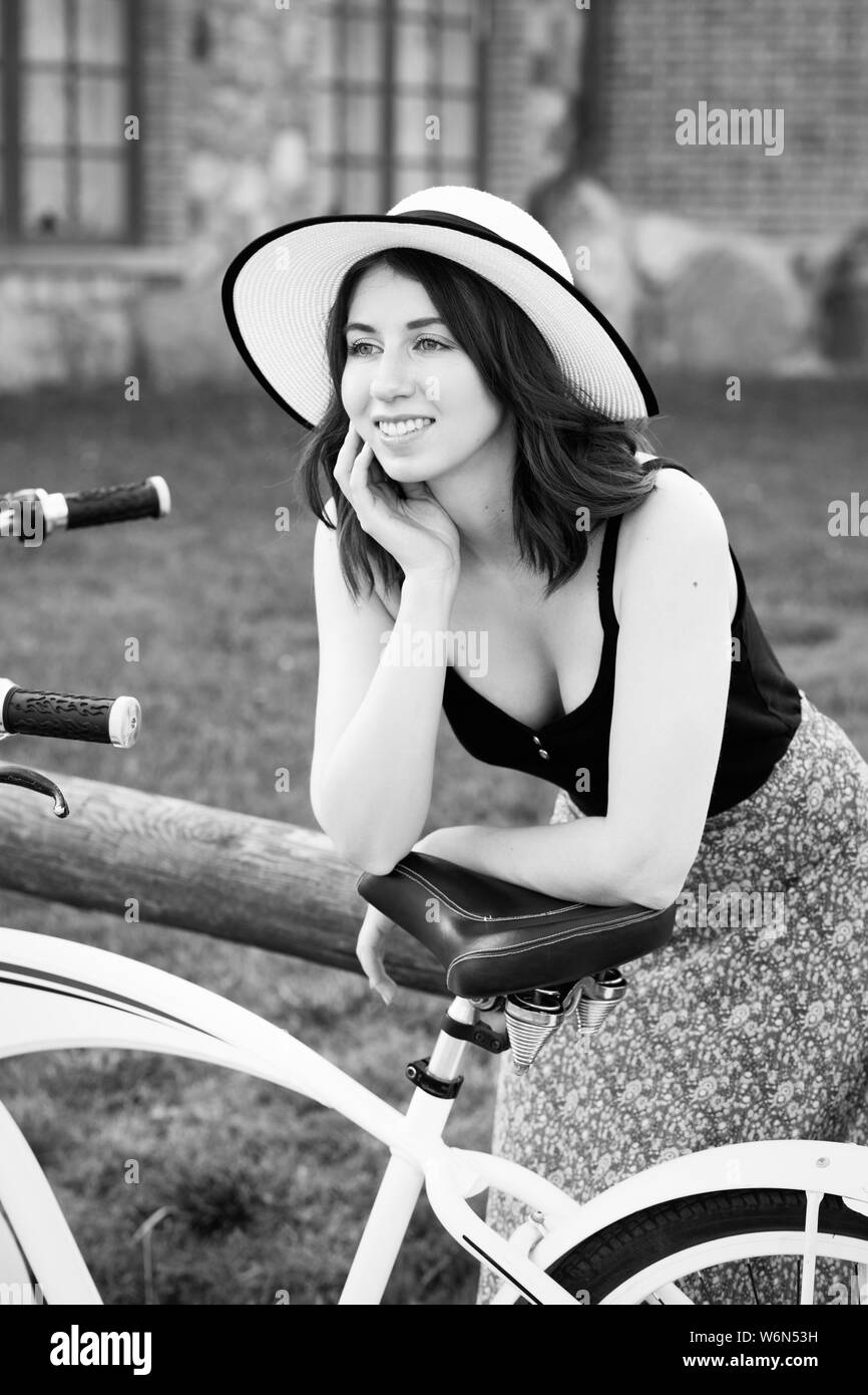 Gerne schönen Mädchen mit Sonnenhut und Fahrrad ausruhen, beiseite, lächelnd, Monochrom Stockfoto