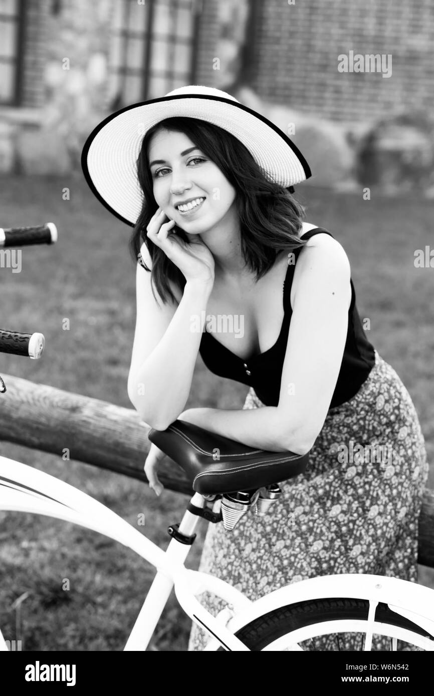 Gerne schönen Mädchen mit Sonnenhut und Fahrrad in die Kamera lächeln, Monochrom Stockfoto