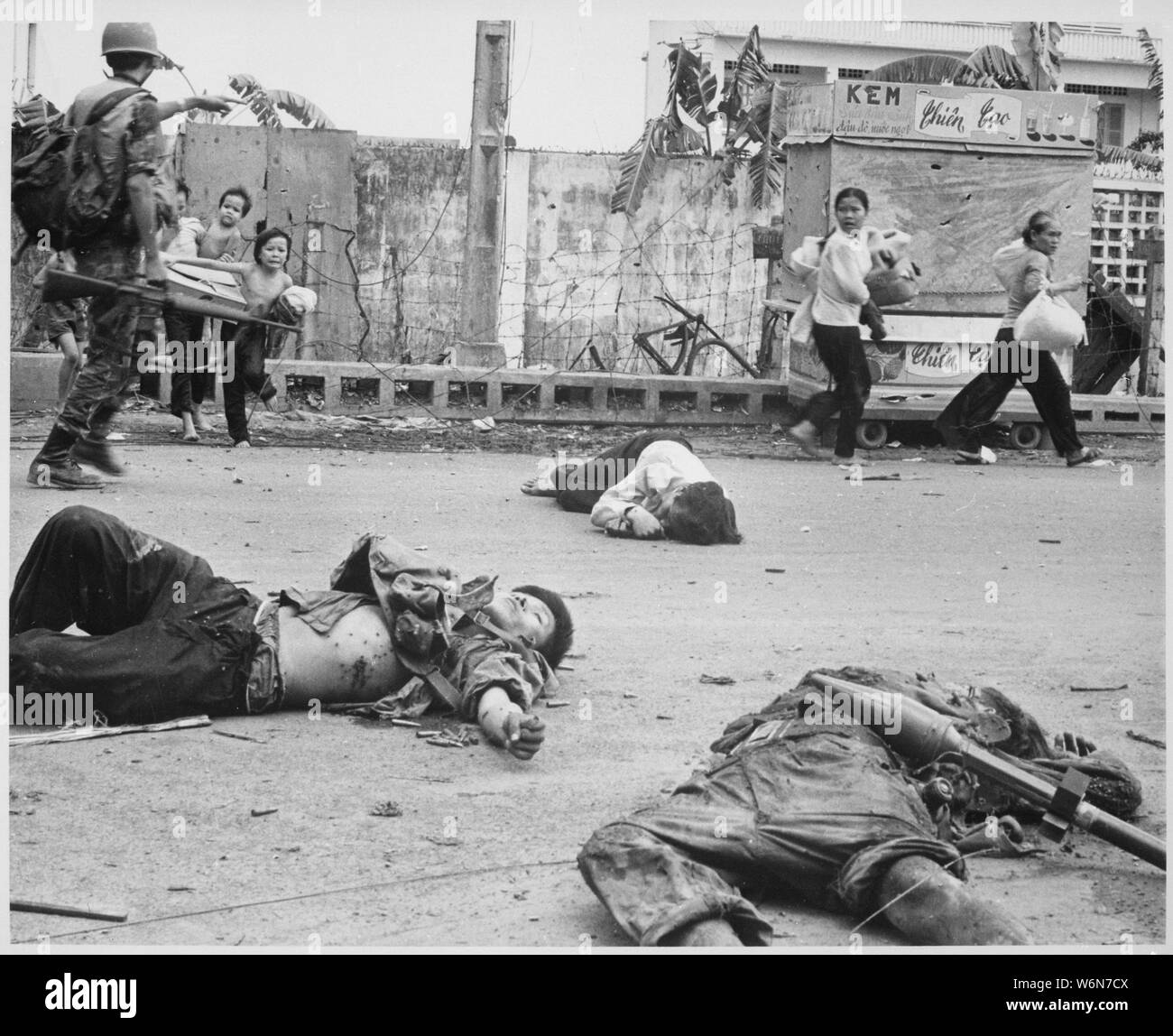 Mit Angst und Besorgnis zeigen auf ihren Gesichtern, und auf Drängen der südvietnamesischen Truppen, Frauen und Kinder mit geborgen Besitz hasten vorbei an den Körper von drei Viet Cong in den Kämpfen getötet., 05/1968; Allgemeine Hinweise: Verwenden Sie Krieg und Konflikt Nummer 423 bei der Bestellung eine Reproduktion oder Anforderung von Informationen zu diesem Bild. Stockfoto