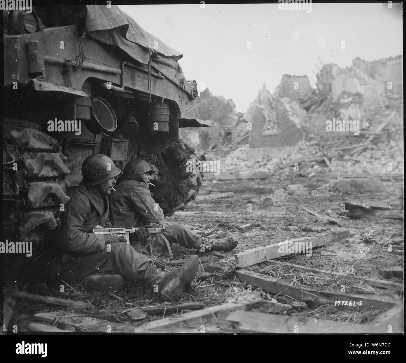 Mit deutschen Schalen schreien Overhead, Amerikanische Infanteristen suchen Schutz hinter einem Panzer. Im Hintergrund können die Ruinen der Stadt Geich, Deutschland, die immer noch unter schweren Beschuss wird gesehen werden.; Allgemeine Hinweise: Verwenden Sie Krieg und Konflikt Nummer 1090 bei der Bestellung eine Reproduktion oder Anforderung von Informationen zu diesem Bild. Stockfoto