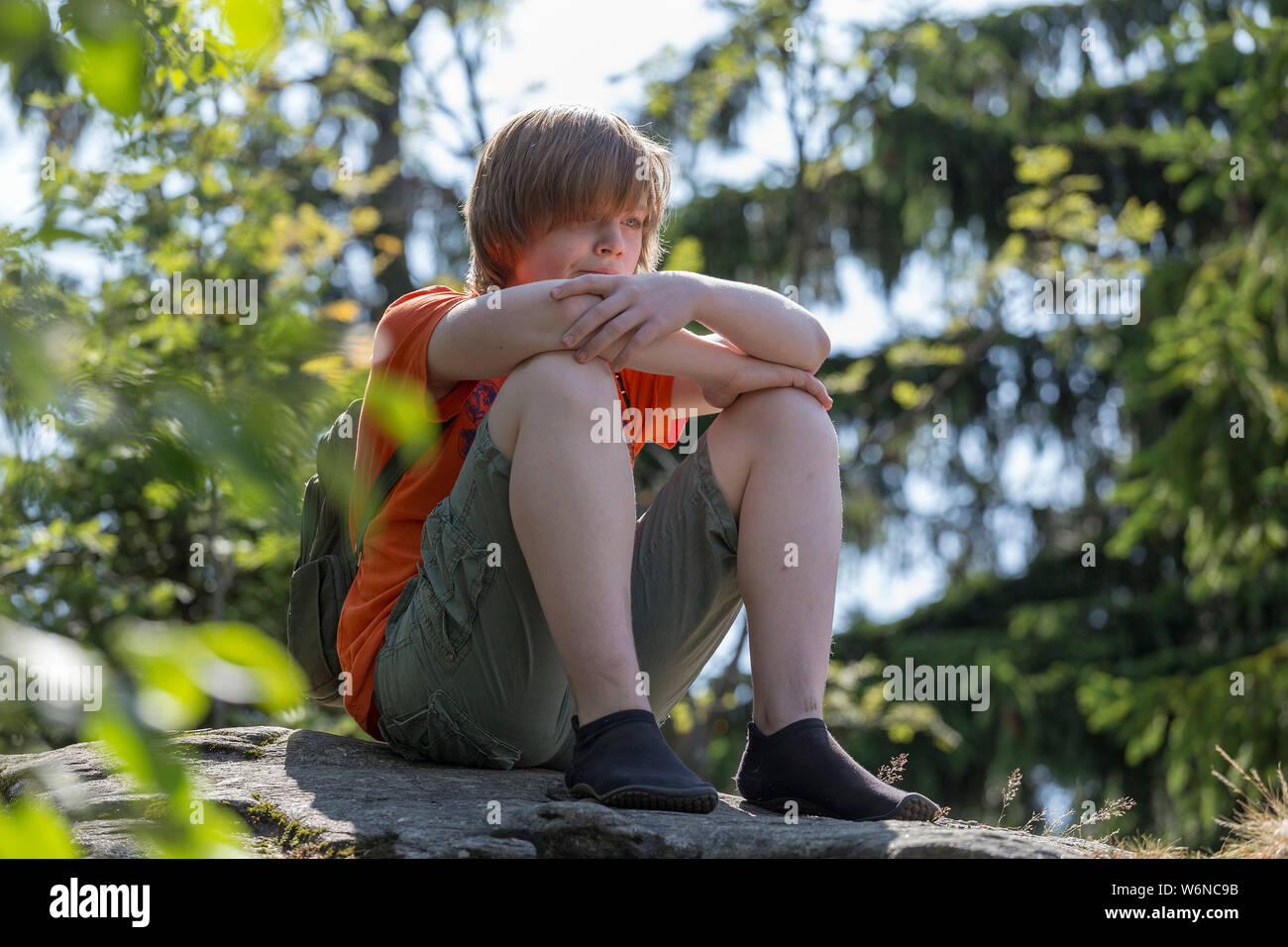 Müde Junge mit minimalistische Schuhe ruht auf dem Gipfel, Großer Riedelstein, Eck, Bayerischer Wald, Bayern, Deutschland Stockfoto