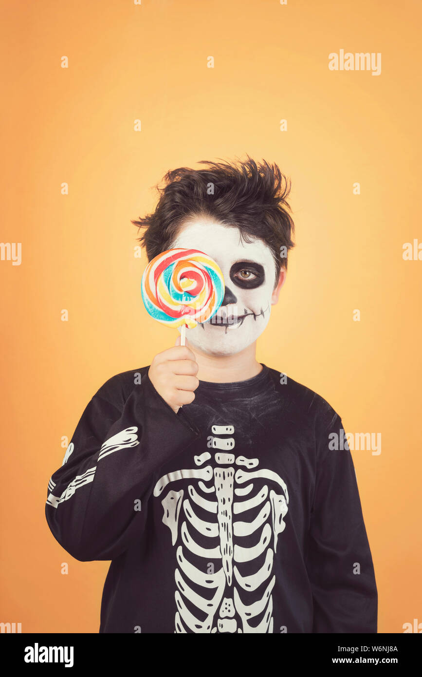 Happy Halloween. lustig Kind in einem Skelett Kostüm für Auge mit Lutscher  gegen orange Hintergrund Stockfotografie - Alamy