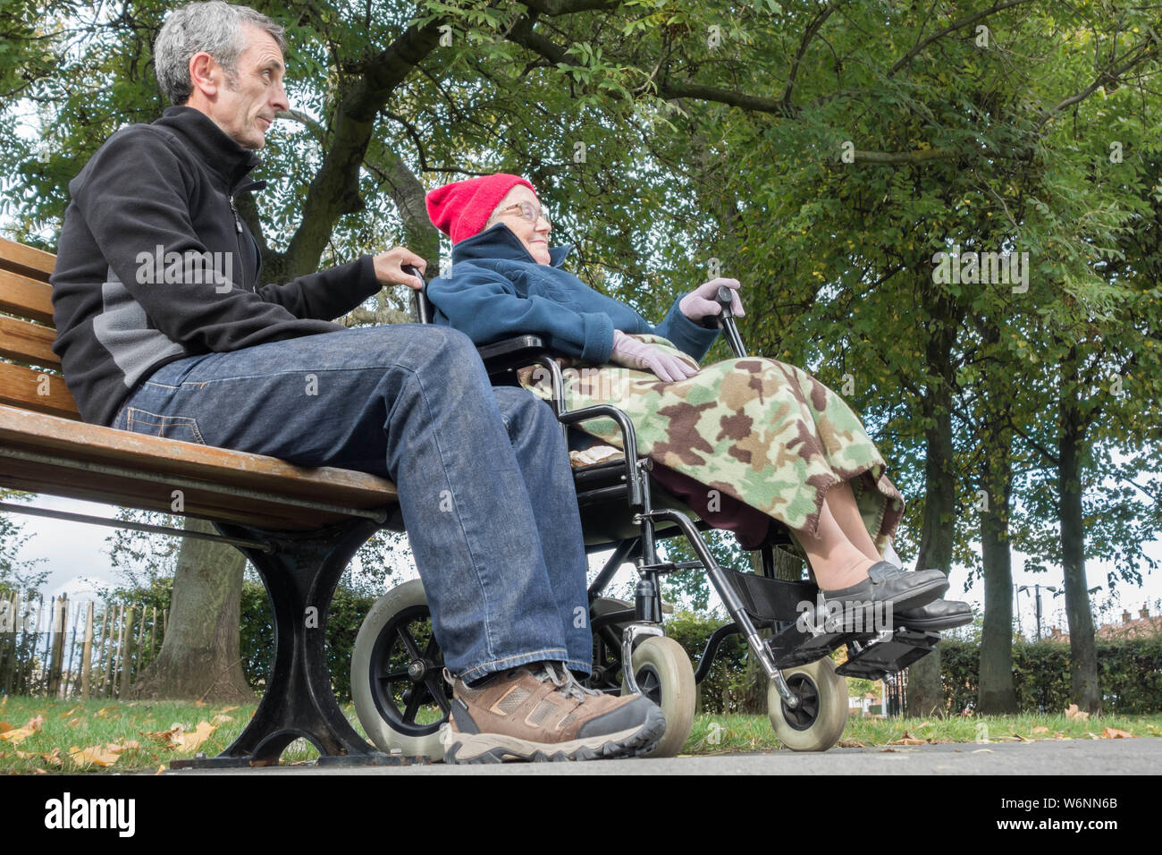 Betreuungsperson (Sohn) mit dem 90 Jahre alten Mutter im Rollstuhl in den öffentlichen Park. Großbritannien Stockfoto