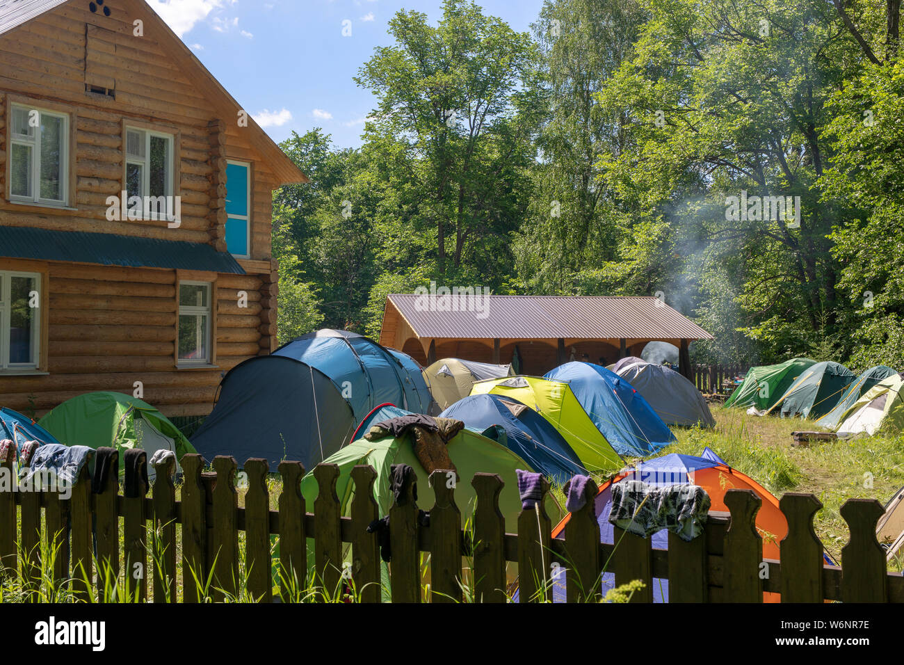 Eingezäunt und bewacht Camping mit Zelt. In der Nähe des Hauses, Pavillon und einen Platz für ein Feuer. Die Dinge sind Trocknen auf dem Zaun. Stockfoto