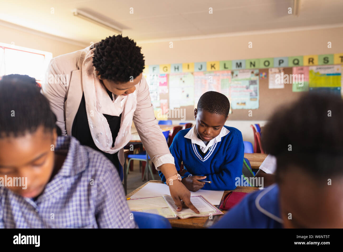 Lehrer Schüler helfen in eine Lektion an einem Township School Stockfoto