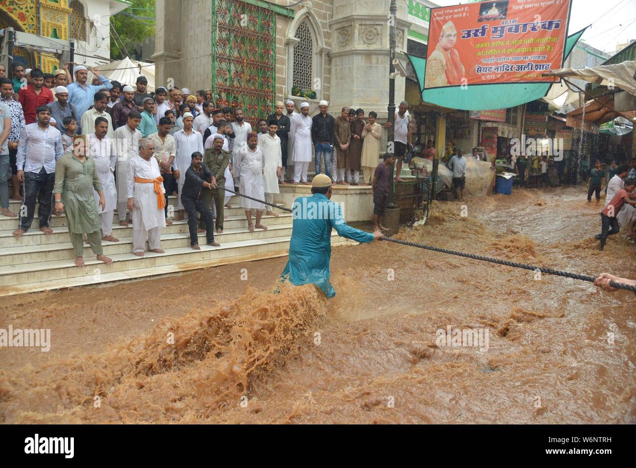 Menschen gehen durch hetzen, Hochwasser, wie Sie auf einem Seil zu halten, um Ihnen zu helfen, die Straße nach schweren Monsunregen außerhalb der Moinuddin Chishti sufi Heiligtum in Ajmer im westlichen Indischen Bundesstaat Rajasthan Kreuz versuchen. (Foto von shaukat Ahmed/Pacific Press) Stockfoto