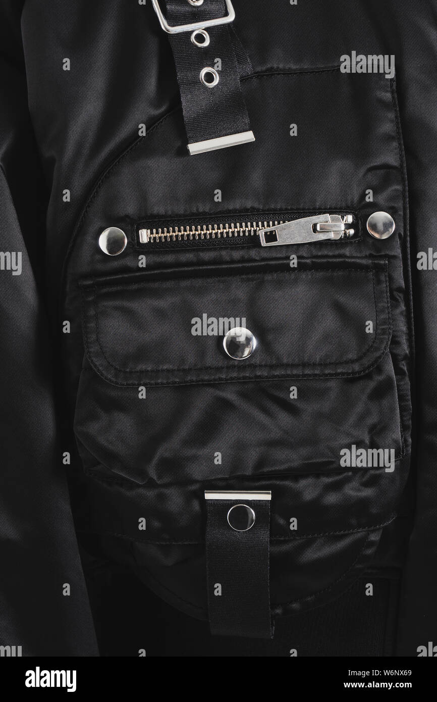 Teil einer Schwarz modische Jacke mit verschiedenen Taschen, Reißverschluss, Gürtel und Tasten. Nahaufnahme einer bequeme Kleidung. Beispiel der Hardware. Stockfoto