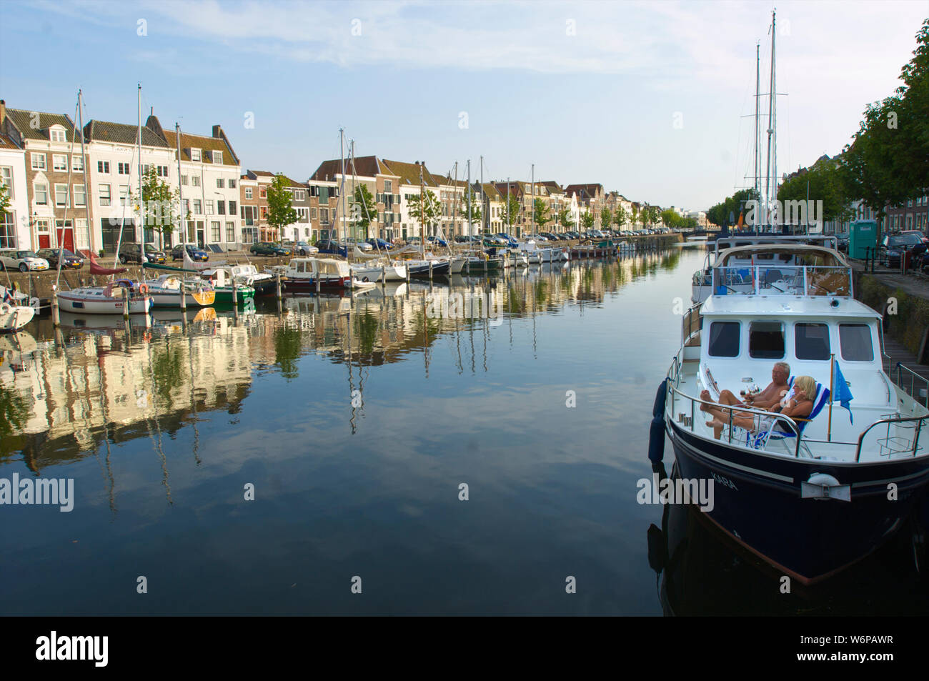 Ein paar sitzen auf Ihrem Boot und schauen sich die Kinderdijk mit historischen Gebäuden in der Stadt Middelburg, Niederlande Stockfoto