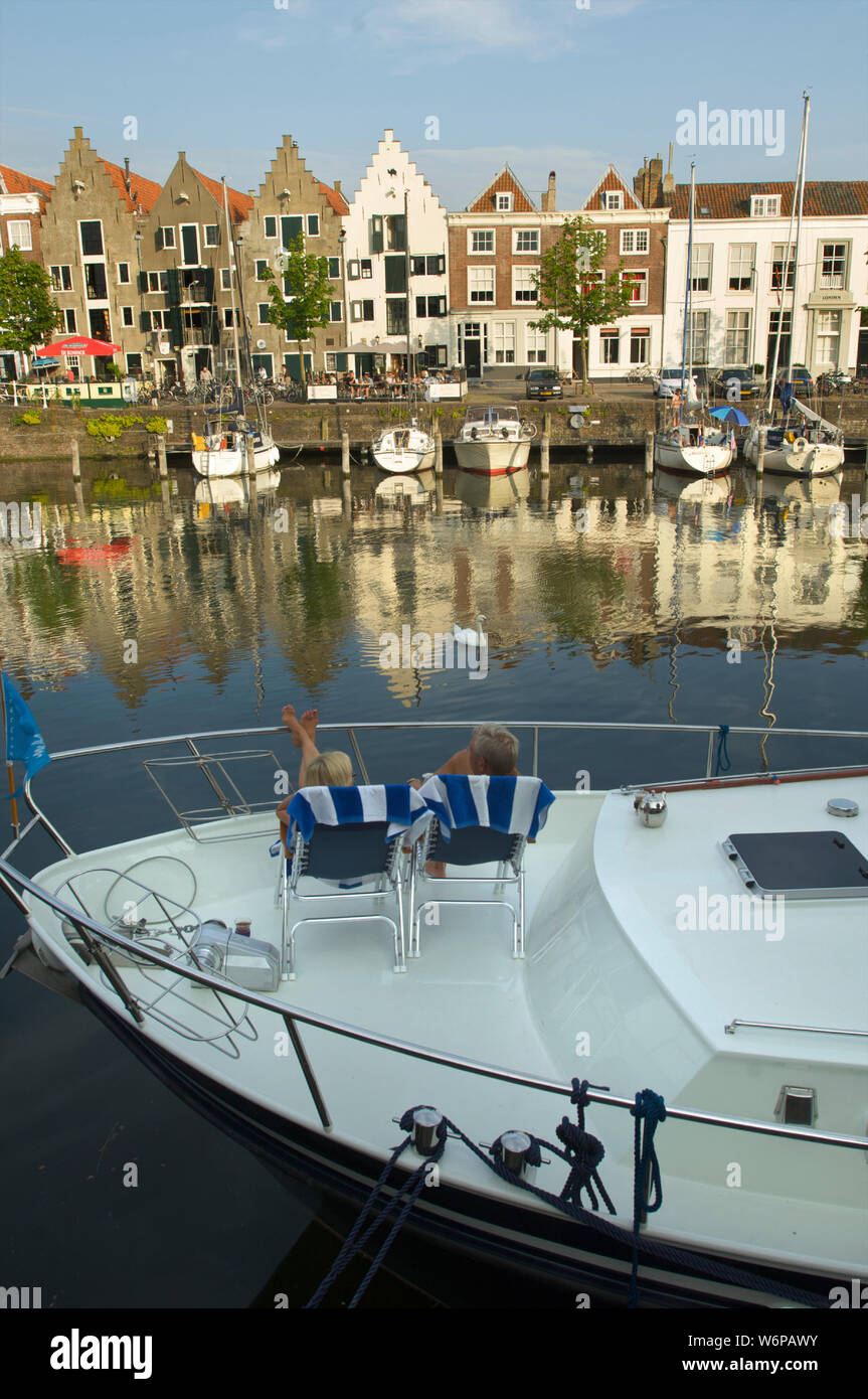 Ein paar sitzen auf Ihrem Boot und schauen sich die Kinderdijk mit historischen Gebäuden in der Stadt Middelburg, Niederlande Stockfoto