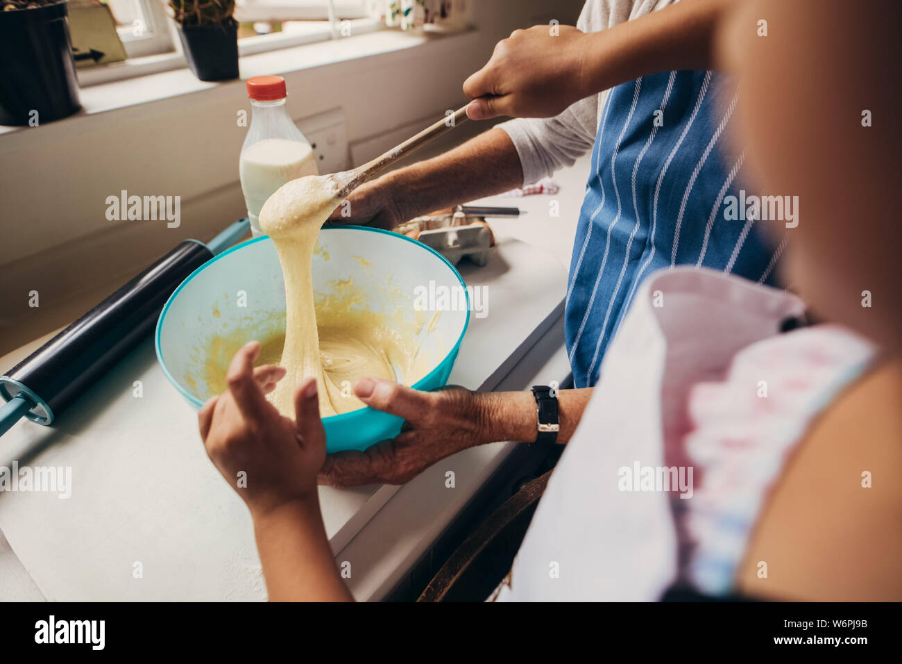 In der Nähe der Hände von zwei Menschen, die kuchenteig. Frauen mischen Teig in eine Schüssel geben und in der Küche. Stockfoto