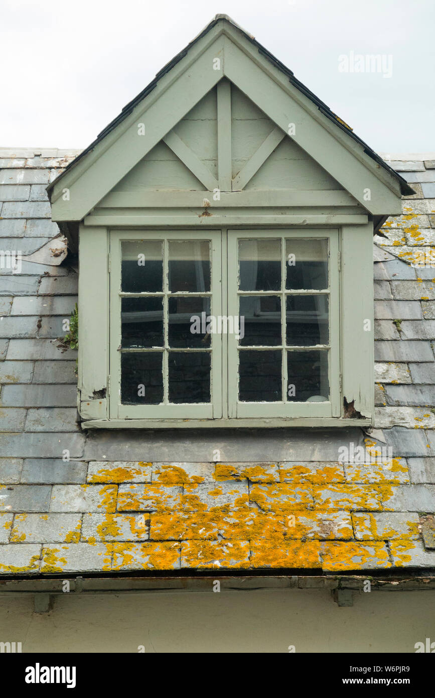 Dach Fenster für ein Zimmer im Dachgeschoss, wo das Holz verrottet ist, die Schieferplatten lose Kommen & das rostige marode Dachrinne verfault und undicht. England UK (110) Stockfoto