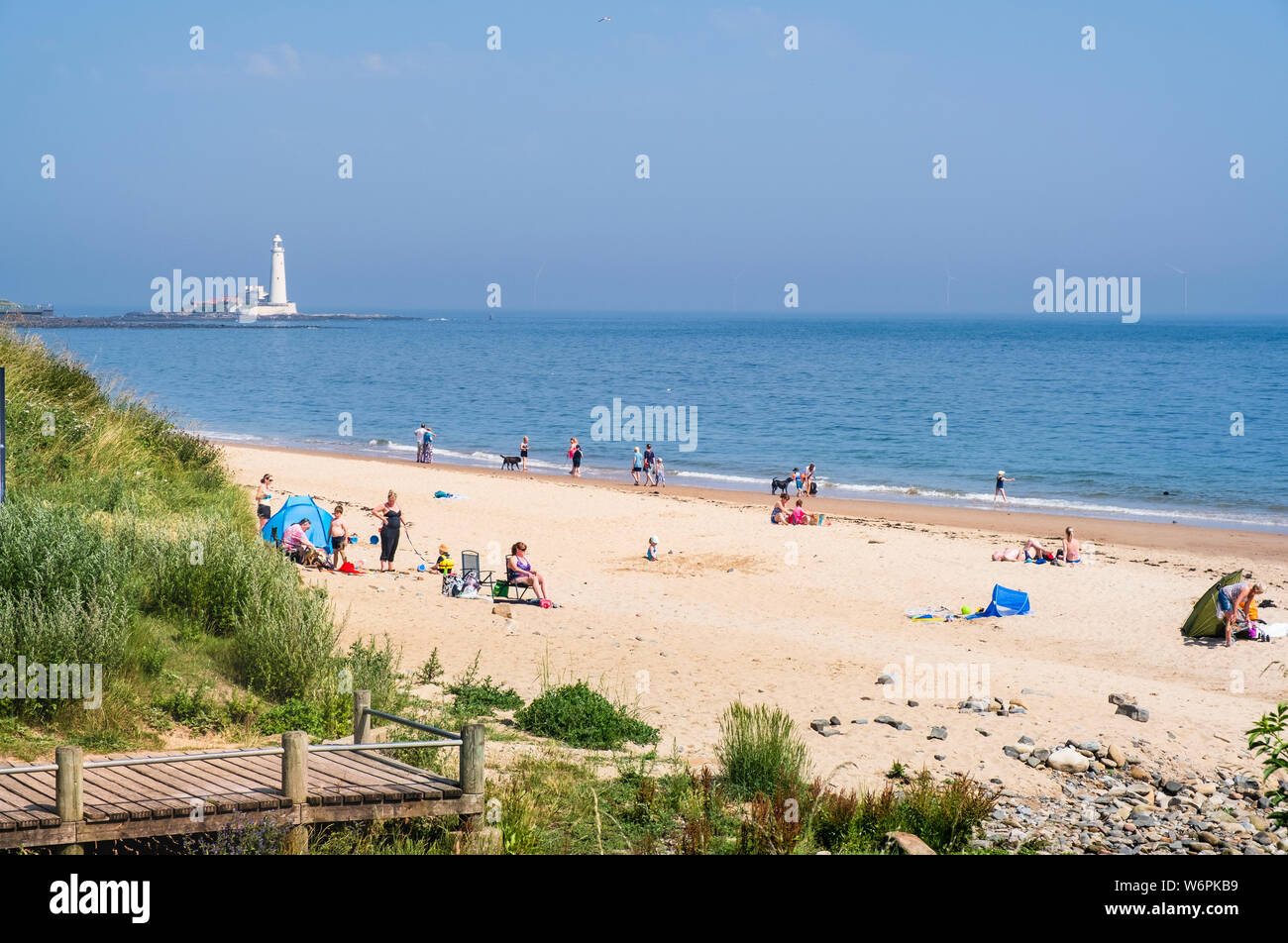 Sommer am Meer, in dem Familien einen sonnigen Tag auf dem langen Sandstrand an der Küste von North Tyneside in Whitley Bay in Tyne genießen und Verschleiß Stockfoto