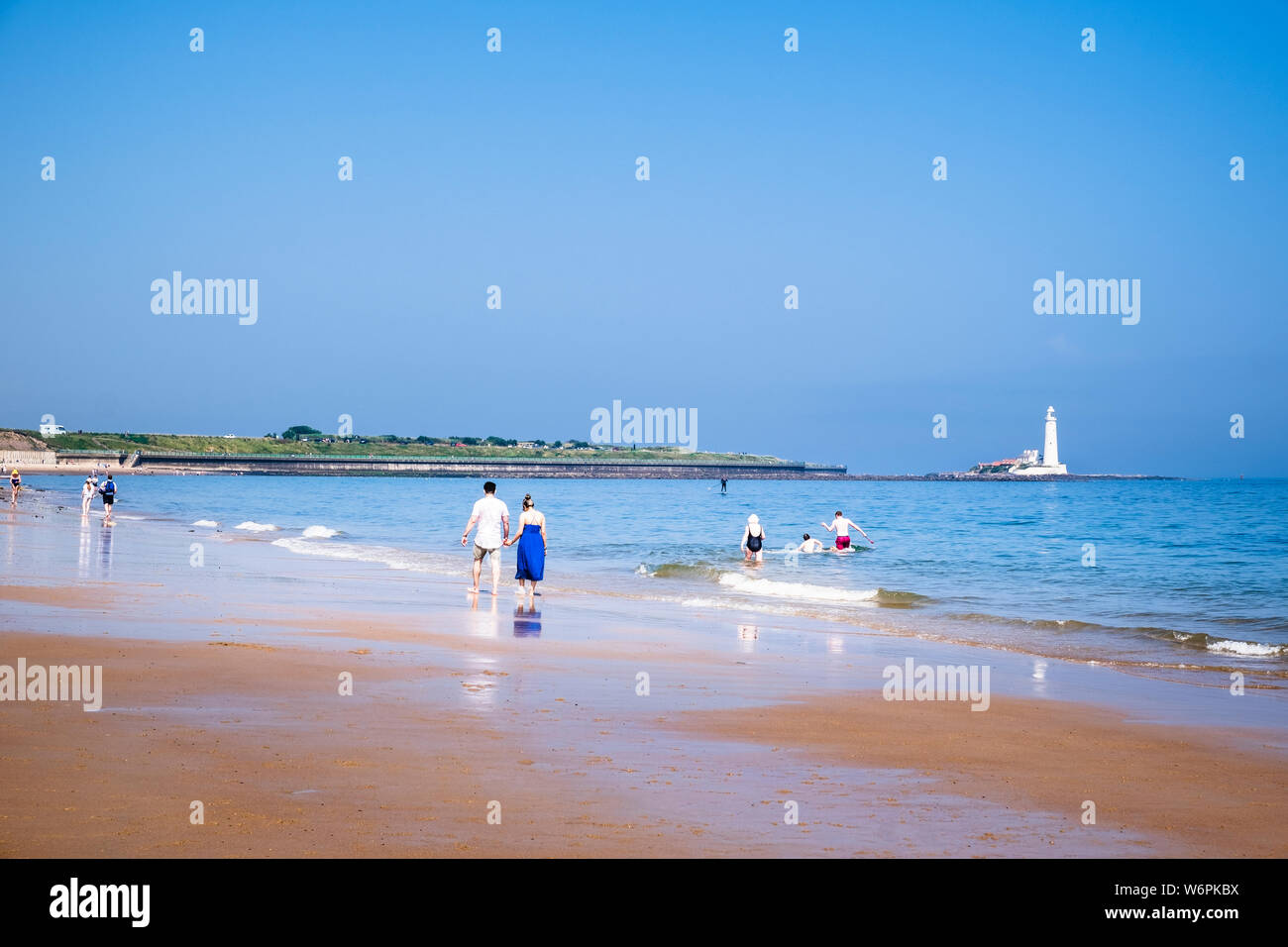 Sommer am Meer, wo Familien und Paare, die einen sonnigen Tag auf dem langen Sandstrand an der Küste von North Tyneside in Whitley Bay in Tyne genießen und Verschleiß Stockfoto