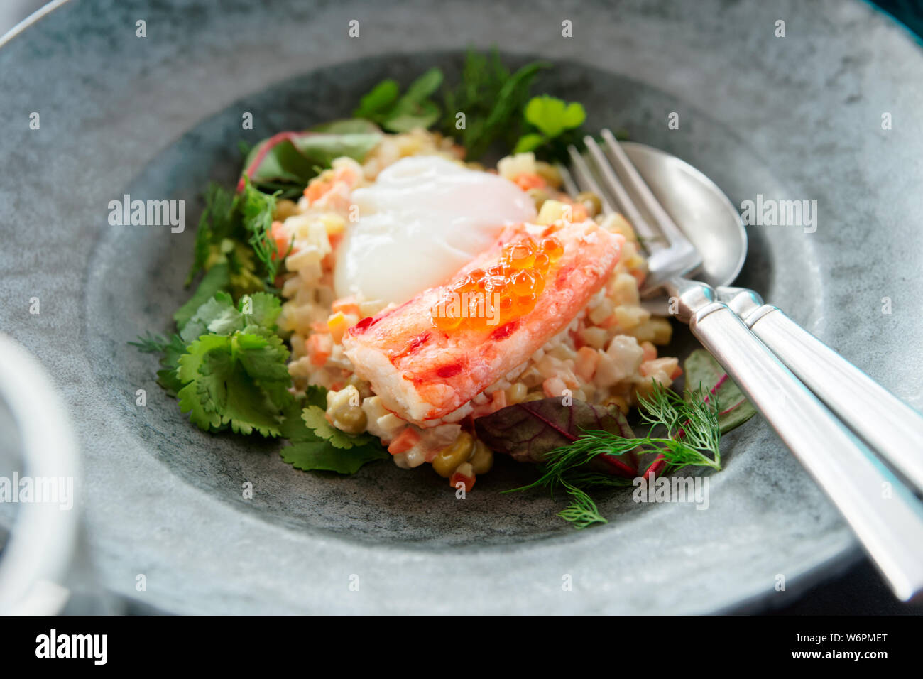 Russischer Salat mit Krabben Bein und pochiertem Ei in Steinzeug Platte Stockfoto