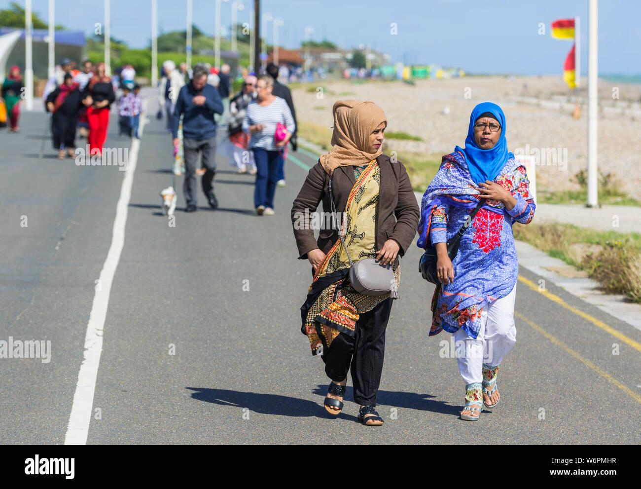 Asiatische Frauen in der Sonne entlang der Strandpromenade am Meer in Großbritannien. Stockfoto