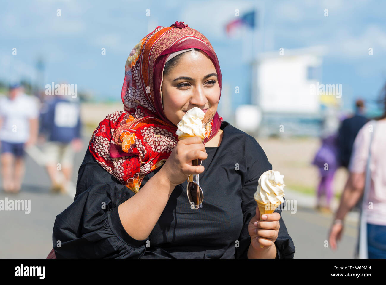 Junge asiatische Frau Essen a 99 Eis am Meer im Sommer in Großbritannien. Stockfoto