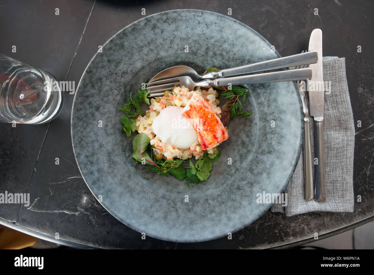 Russischer Salat mit Krabben Bein und pochiertem Ei in Steinzeug Platte geschossen von oben Stockfoto
