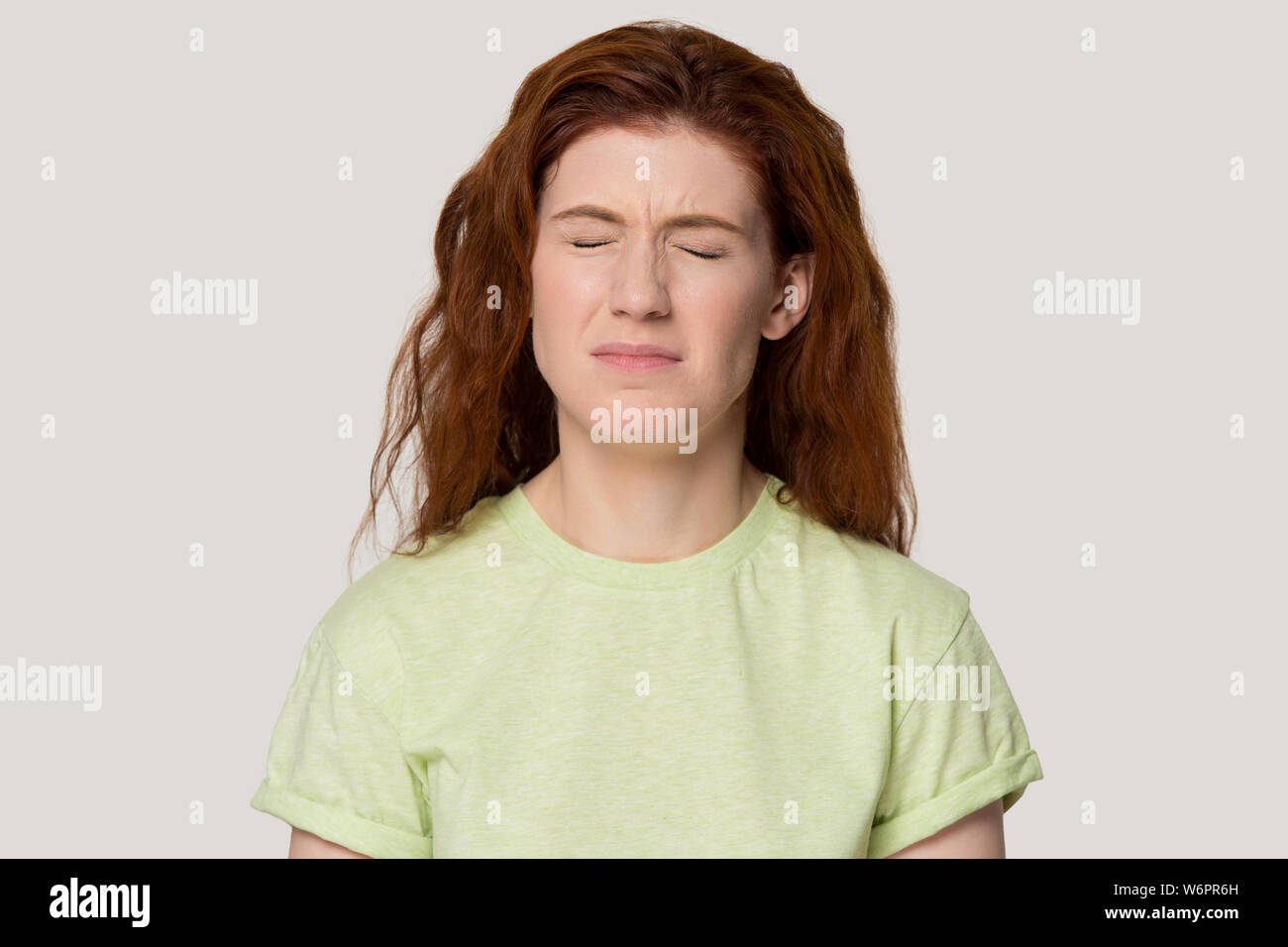 Redhead unglücklich kapriziöse Frau geschlossenen Augen runzelte die Augenbrauen studio headshot Stockfoto