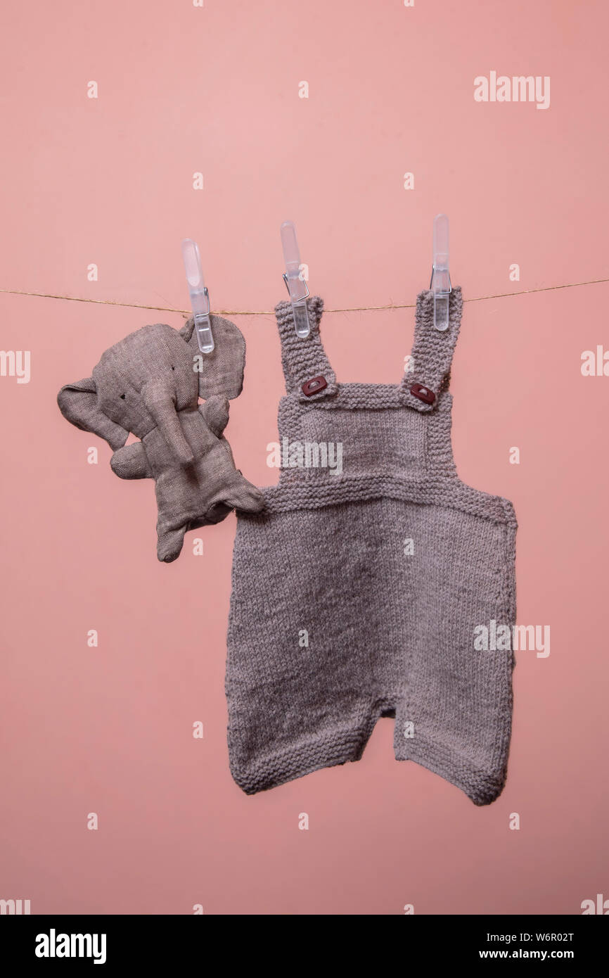 Handarbeit gestrickte Baby Kleidung hängend auf einer Linie mit einem Spielzeug Stockfoto