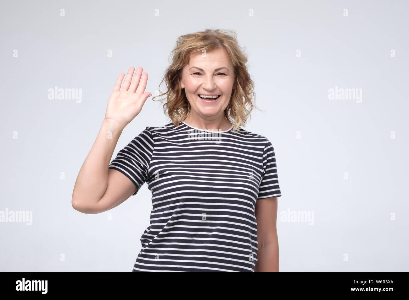 Positive reife kaukasischen lächelnde Frau freundlich und winkende Hand an Kamera Stockfoto